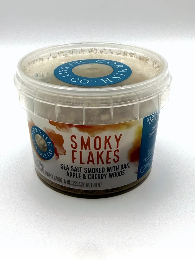 Clear plastic tub of Cornish Sea Salt Co. Smoky Flakes with an orange and white label