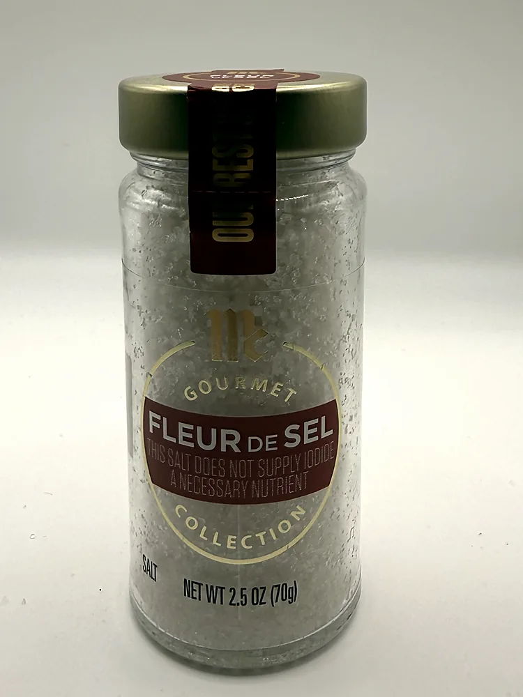 Glass jar of McCormick Gourmet Fleur de Sel with a gold lid and burgundy label