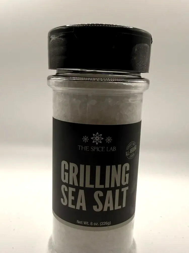 Shaker jar of The Spice Lab Grilling Sea Salt with a black label and black flip-top lid