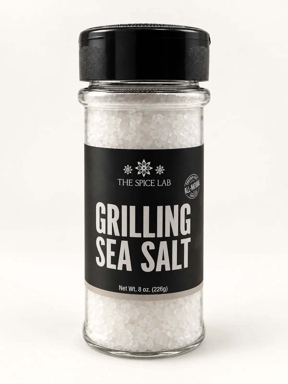 Shaker jar of The Spice Lab Grilling Sea Salt with a black label and black flip-top lid